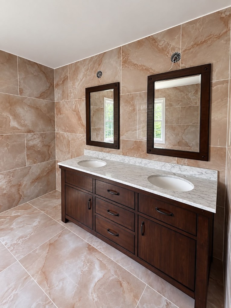 Finished bathroom with marble-look tile and dark wood double vanity