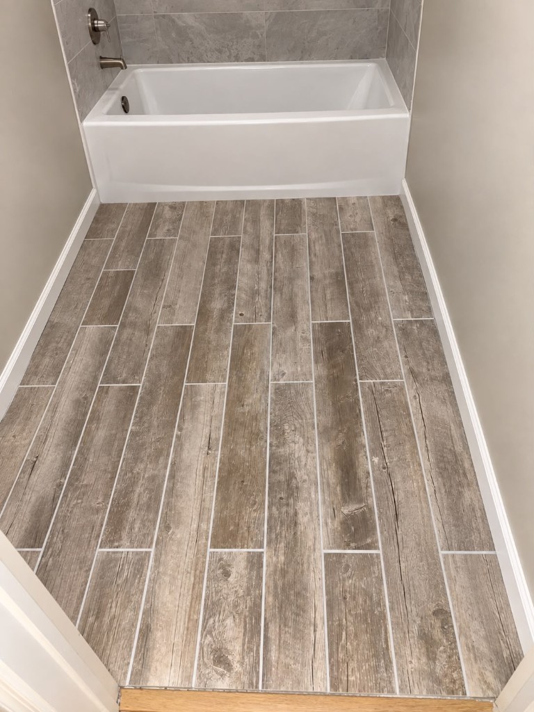 Plank-style ceramic floor tile leading to a bathtub