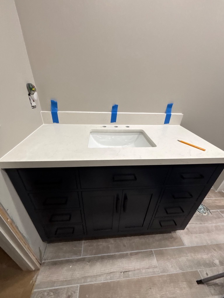 Navy bathroom vanity with white quartz top during install